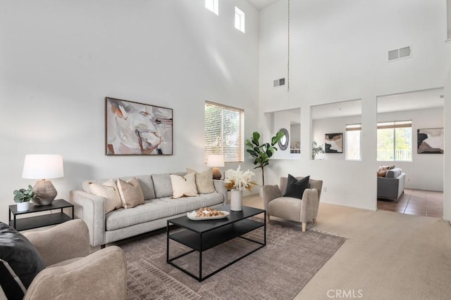 carpeted living room with a towering ceiling and a healthy amount of sunlight