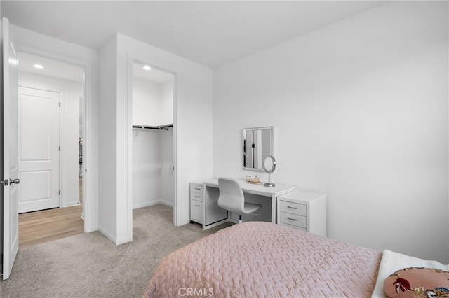 carpeted bedroom featuring a walk in closet and a closet