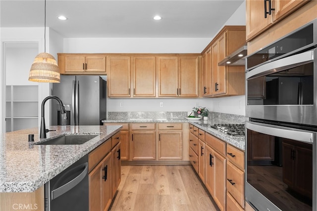 kitchen with pendant lighting, sink, light stone counters, stainless steel appliances, and light hardwood / wood-style flooring