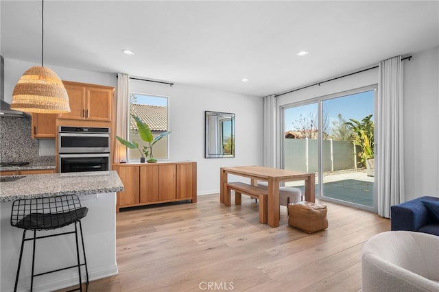 kitchen with pendant lighting, stainless steel double oven, tasteful backsplash, and a wealth of natural light