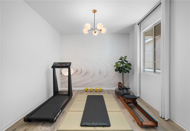 workout room with a notable chandelier and light hardwood / wood-style flooring