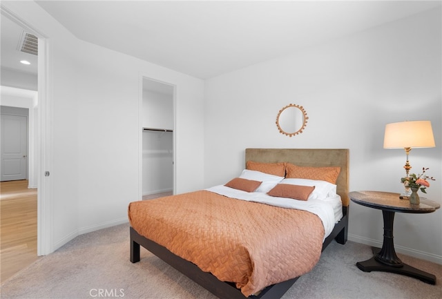 bedroom featuring light carpet, a walk in closet, and a closet