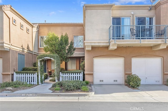 view of front of home with fence, concrete driveway, stucco siding, a balcony, and an attached garage