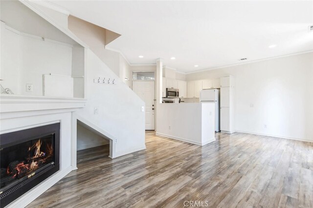 unfurnished living room with crown molding and hardwood / wood-style floors