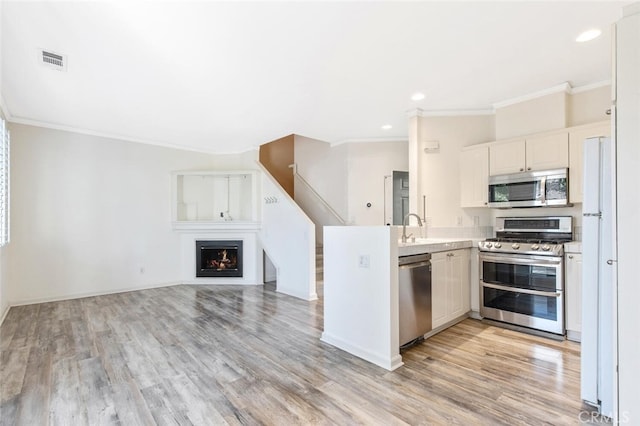 kitchen featuring white cabinetry, stainless steel appliances, crown molding, light hardwood / wood-style flooring, and sink