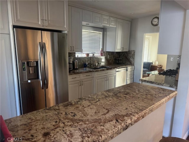 kitchen featuring backsplash, kitchen peninsula, sink, white cabinetry, and appliances with stainless steel finishes