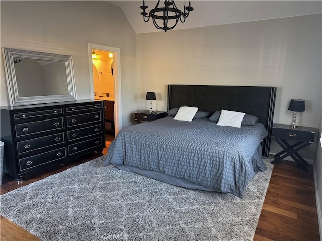 bedroom with dark wood-type flooring, lofted ceiling, connected bathroom, and an inviting chandelier