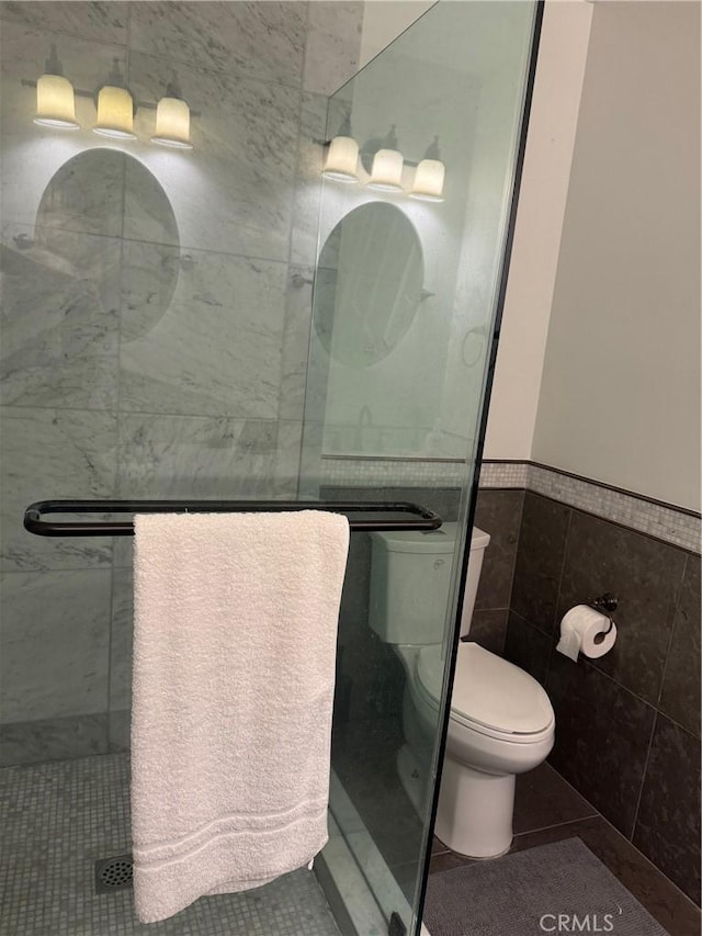 bathroom featuring toilet, tile patterned flooring, and tile walls