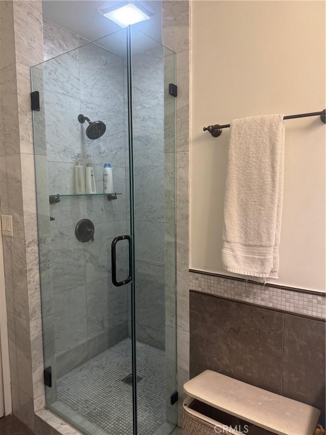 bathroom featuring an enclosed shower and tile walls