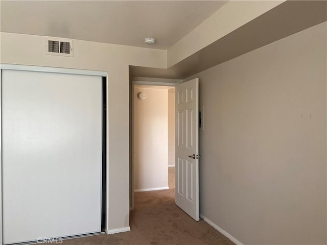 unfurnished bedroom with light carpet and a closet