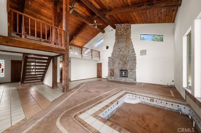 unfurnished living room with a stone fireplace, wooden ceiling, high vaulted ceiling, beam ceiling, and tile patterned floors