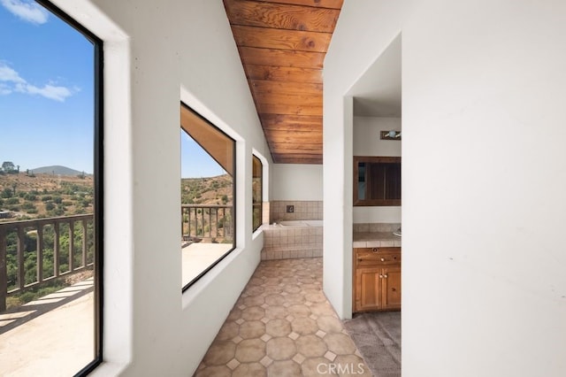 hall with a mountain view, vaulted ceiling, and wooden ceiling