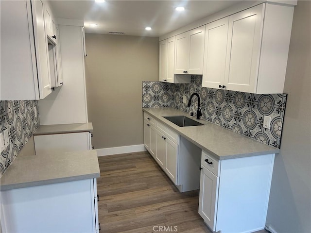 kitchen featuring dark wood-type flooring, sink, backsplash, and white cabinets