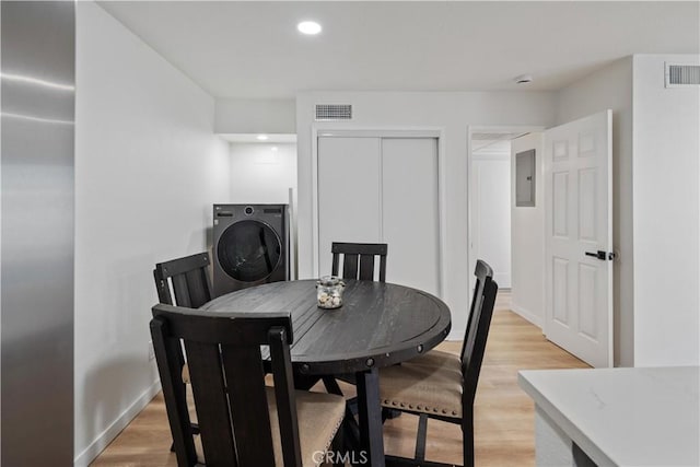 dining room with electric panel, light wood-type flooring, and washer / clothes dryer