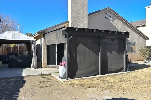 back of property with stucco siding, a patio, and a gazebo