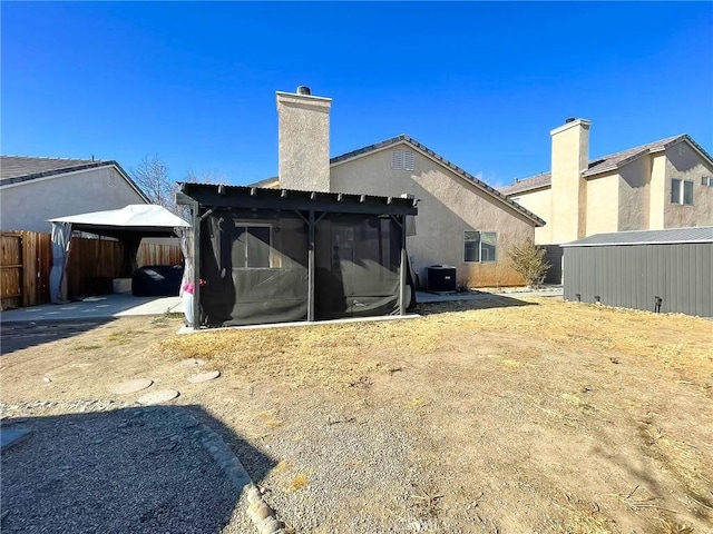 rear view of house with a chimney, a gazebo, and stucco siding