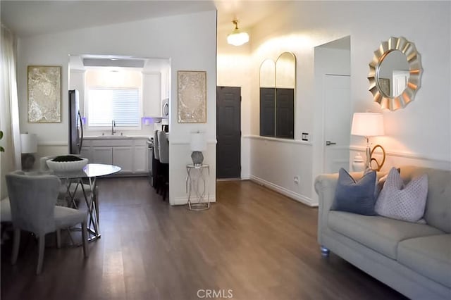 living area featuring lofted ceiling, dark wood-type flooring, and baseboards