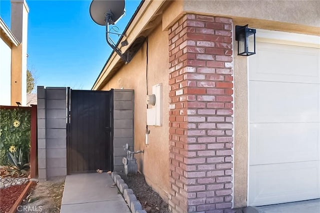 view of side of property with a garage, a gate, brick siding, and fence