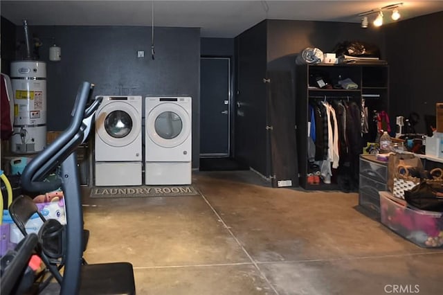 clothes washing area featuring secured water heater, washer and clothes dryer, and laundry area