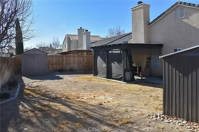 exterior space with a fenced backyard, an outdoor structure, and a storage unit