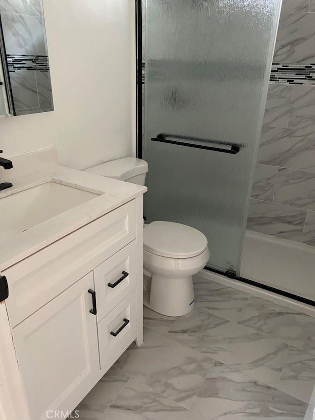 bathroom with a shower with shower door, vanity, and toilet