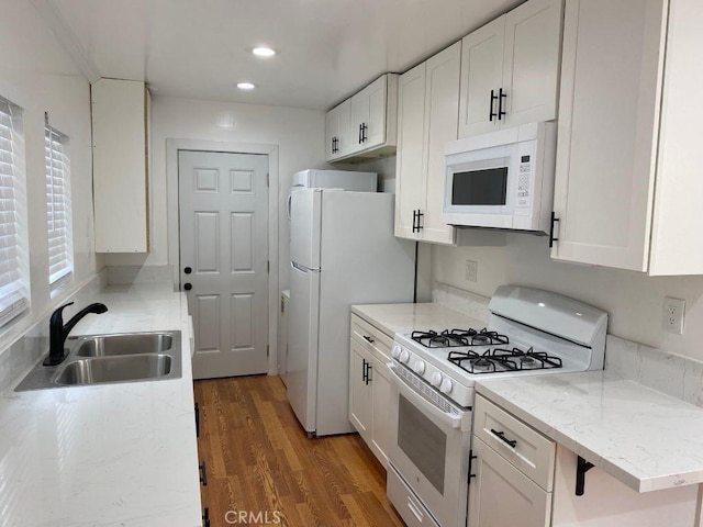 kitchen featuring hardwood / wood-style flooring, sink, white cabinets, and white appliances