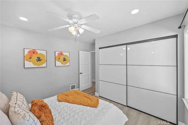 bedroom featuring ceiling fan, a closet, and light wood-type flooring