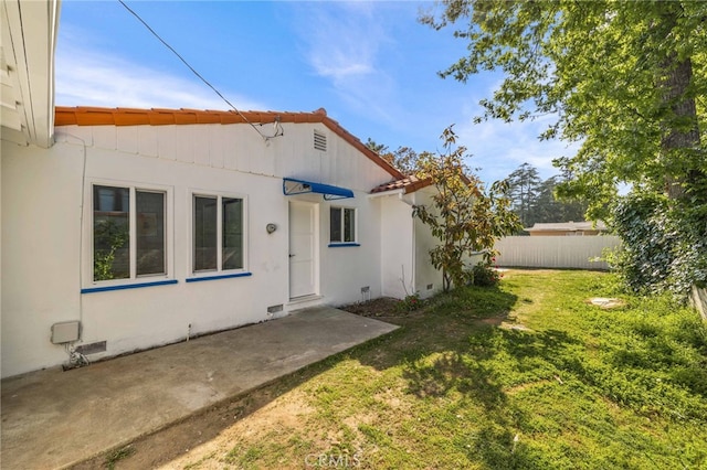 back of house with a lawn and a patio