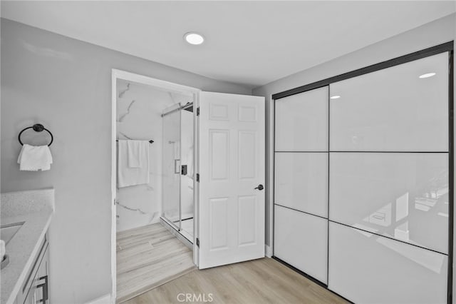 bathroom with walk in shower, vanity, and hardwood / wood-style floors