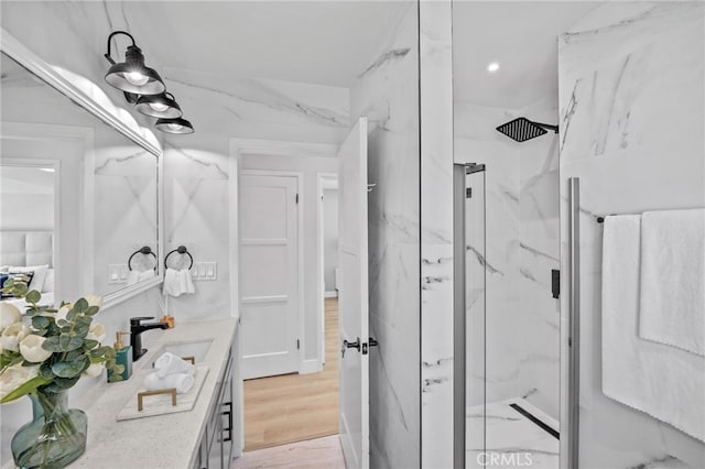 bathroom with a shower with shower door, vanity, and wood-type flooring