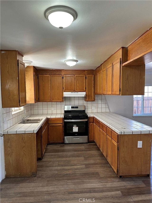 kitchen with stainless steel range with gas stovetop, tile counters, dark hardwood / wood-style floors, tasteful backsplash, and sink