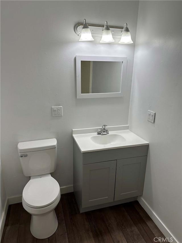 bathroom with toilet, vanity, and hardwood / wood-style flooring