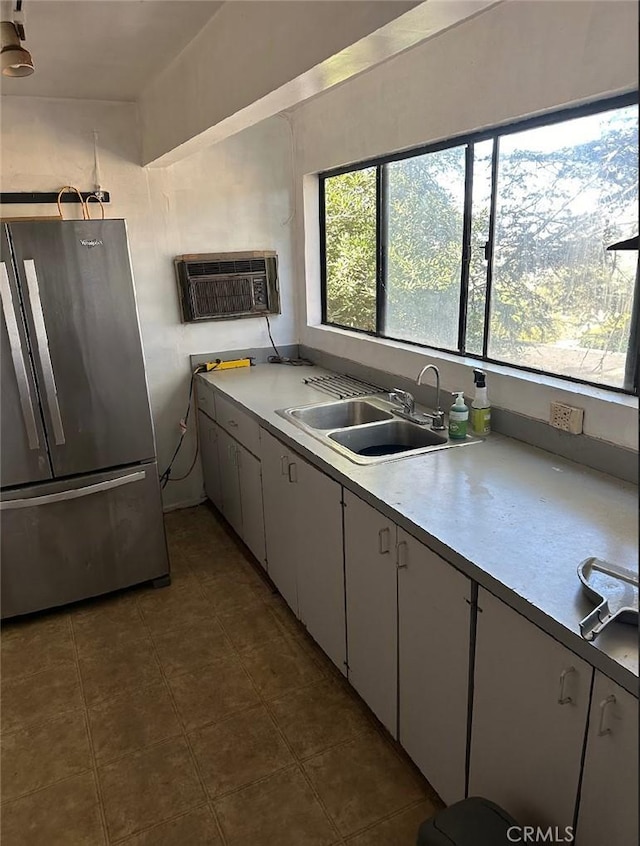 kitchen with sink, white cabinetry, stainless steel fridge, and a wall mounted AC