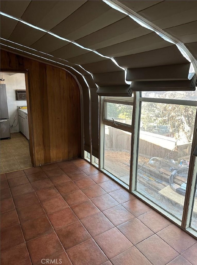 interior space featuring stainless steel fridge, wooden walls, and tile patterned flooring