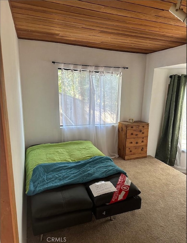 bedroom with wooden ceiling, carpet, and multiple windows