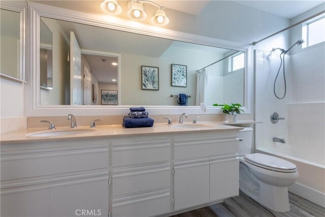 full bathroom featuring wood-type flooring, shower / bath combo with shower curtain, a wealth of natural light, and vanity