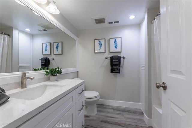 bathroom with wood-type flooring, toilet, and vanity