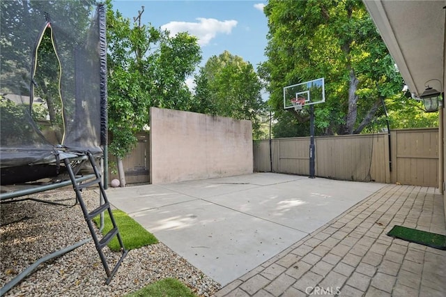 view of patio / terrace featuring basketball hoop and a trampoline