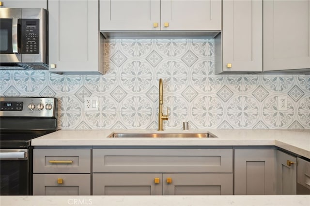 kitchen featuring sink, gray cabinets, stainless steel appliances, and tasteful backsplash