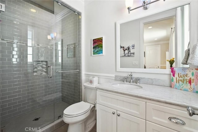 bathroom featuring toilet, ornamental molding, an enclosed shower, and vanity