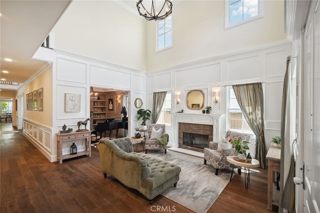 living room with a fireplace, dark hardwood / wood-style floors, a high ceiling, crown molding, and a chandelier