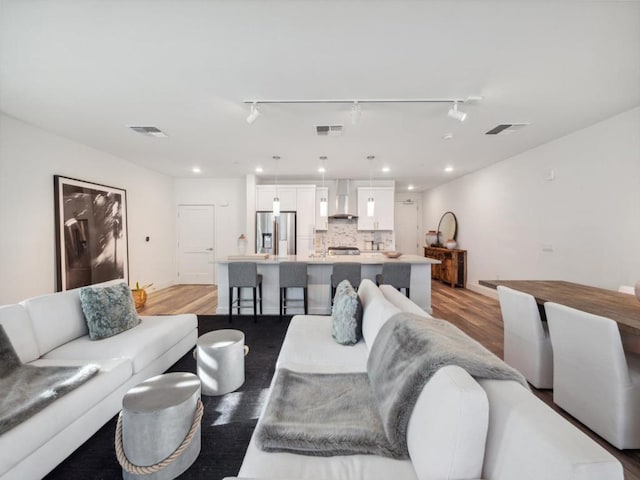 living room featuring rail lighting and light hardwood / wood-style flooring