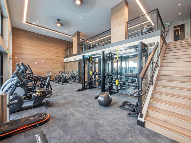 gym with a raised ceiling, a towering ceiling, and wood walls