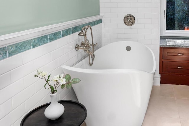 bathroom featuring tile patterned flooring, a tub to relax in, vanity, and tile walls