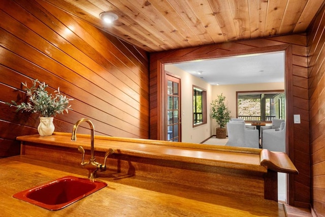 bar with sink, wood ceiling, and wooden walls