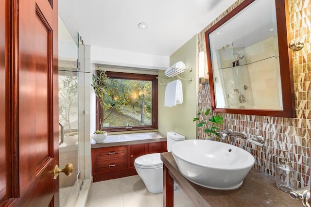 bathroom featuring sink, a shower with door, and toilet