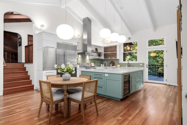 kitchen with pendant lighting, island exhaust hood, beam ceiling, and stainless steel built in fridge