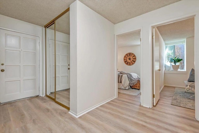 hall with light hardwood / wood-style floors and a textured ceiling