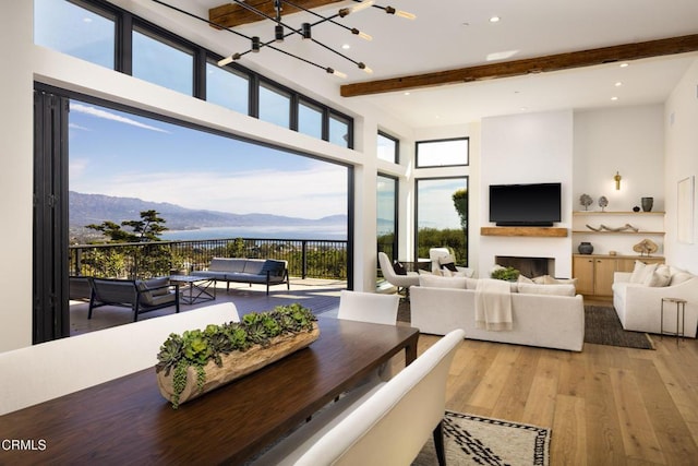 dining room with beamed ceiling, plenty of natural light, a mountain view, and light wood-type flooring