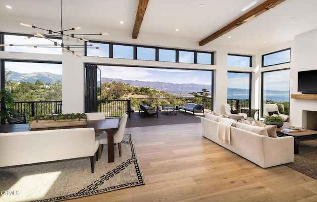 living room featuring beamed ceiling, a mountain view, light hardwood / wood-style floors, and a notable chandelier